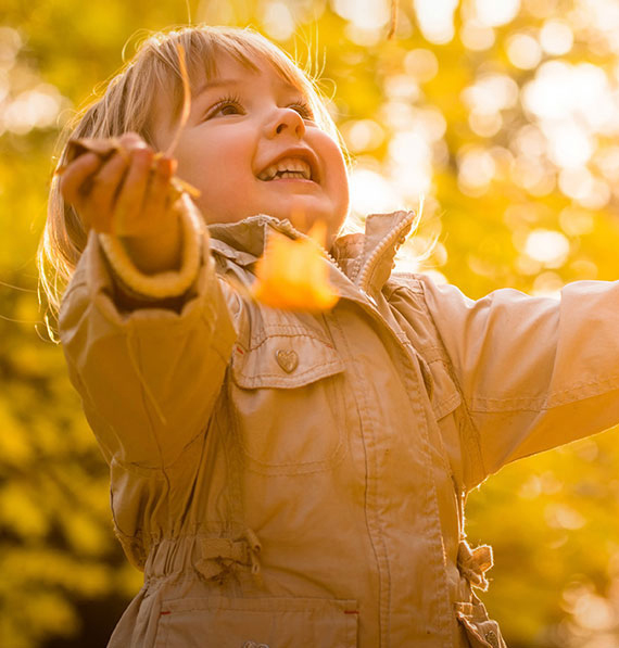 Enfant throwing tree leaves in the air