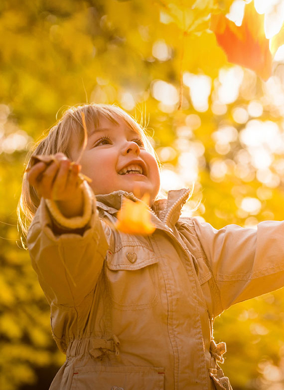 Enfant throwing tree leaves in the air